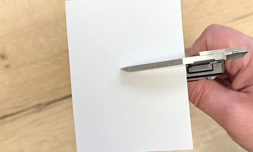 Printpapier tussen de bekken van een digitale schuifmaat voor het reinigen van de meetvlakken